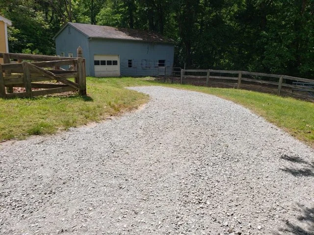 a gravel road leading to a barn